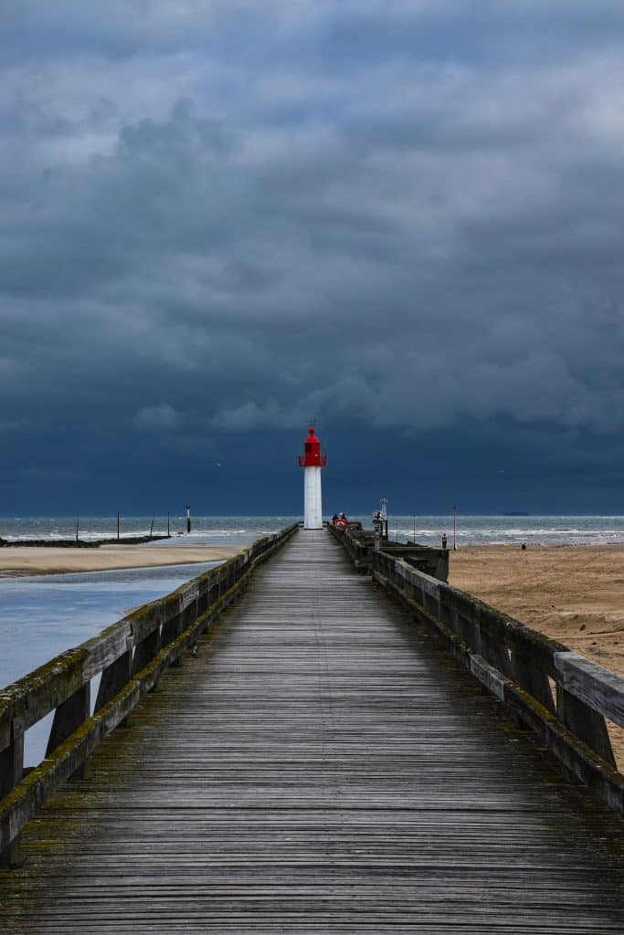 Le phare de Trouville, superbe même pendant la tempête - Photo de <a href="https://unsplash.com/fr/@axpphotography?utm_content=creditCopyText&utm_medium=referral&utm_source=unsplash">AXP Photography</a> sur <a href="https://unsplash.com/fr/photos/une-jetee-en-bois-avec-une-maison-legere-au-loin-7dlSizBYtbY?utm_content=creditCopyText&utm_medium=referral&utm_source=unsplash">Unsplash</a>